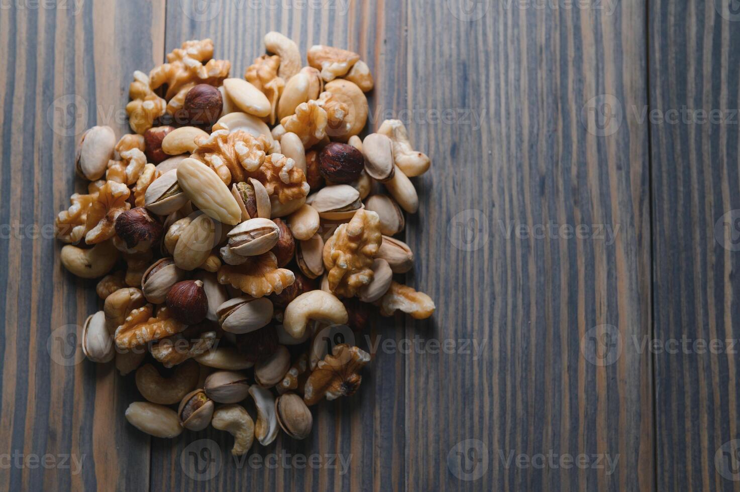 mixed nuts in a bowl on wooden table, top view with copy space. photo