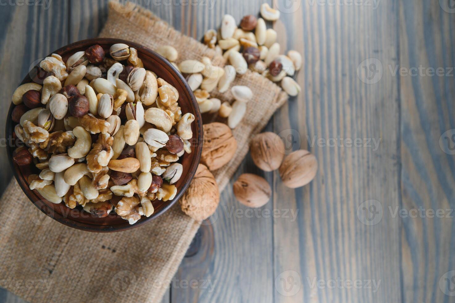mixed nuts in a bowl on wooden table, top view with copy space. photo