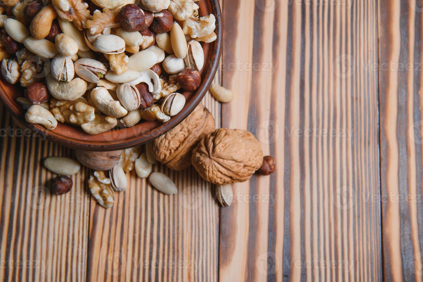 mixed nuts in a bowl on wooden table, top view with copy space. photo