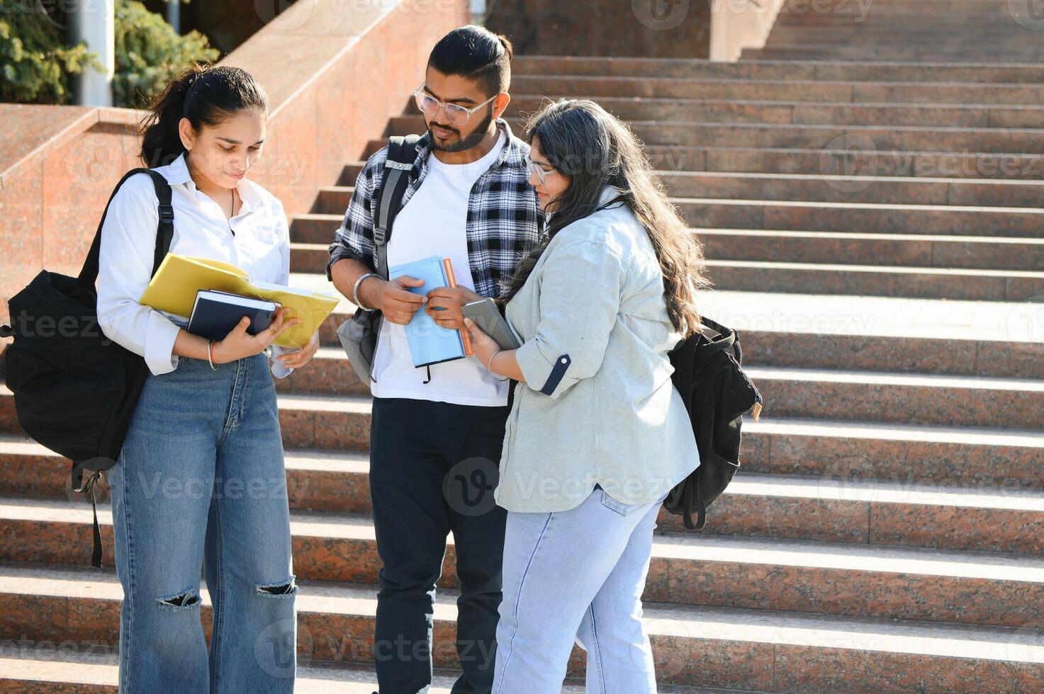 Portrait of three multi-ethnic university students embracing together standing in the campus photo