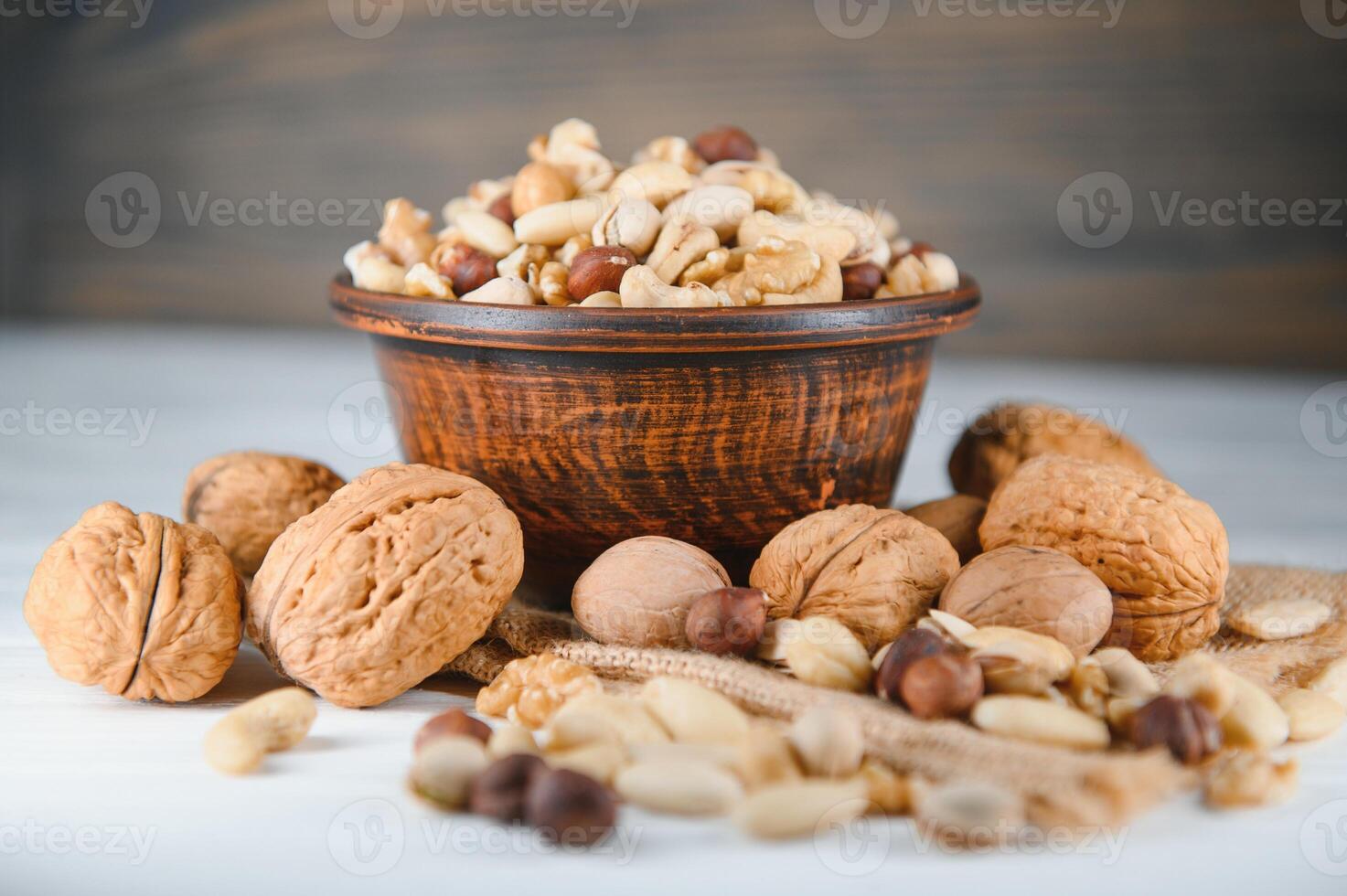 Wooden bowl with mixed nuts on rustic table top view. Healthy food and snack. photo