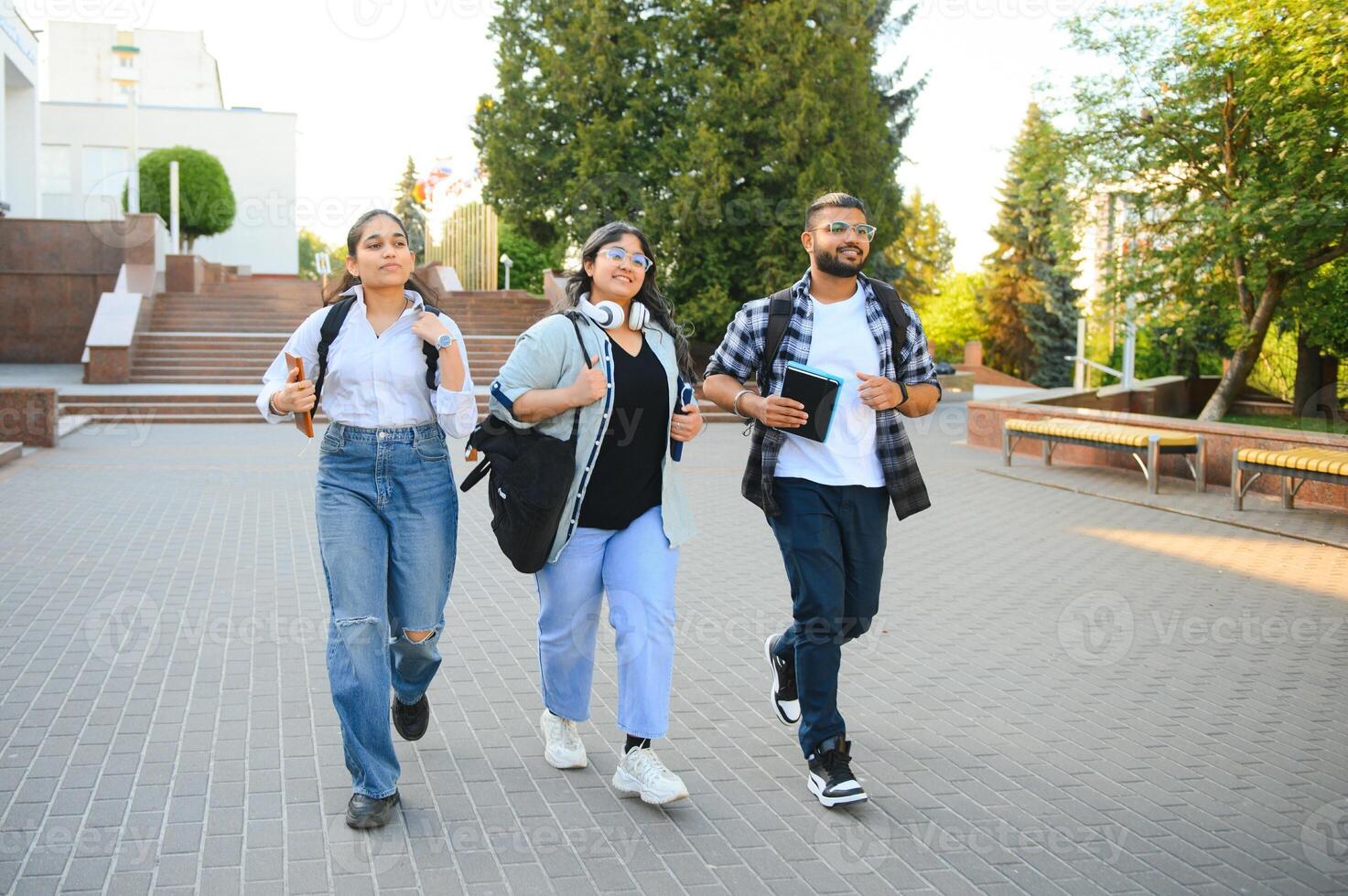 Three international students standing and holding a books photo