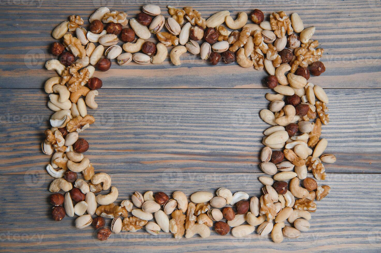 mixed nuts in a bowl on wooden table, top view with copy space. photo