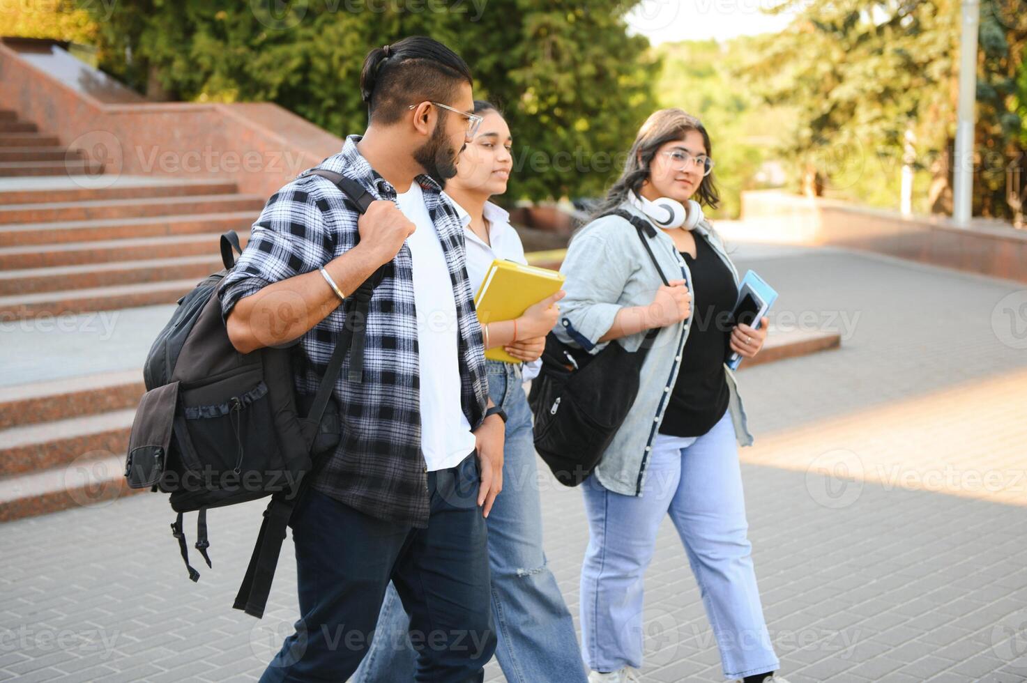 Portrait of three multi-ethnic university students embracing together standing in the campus photo