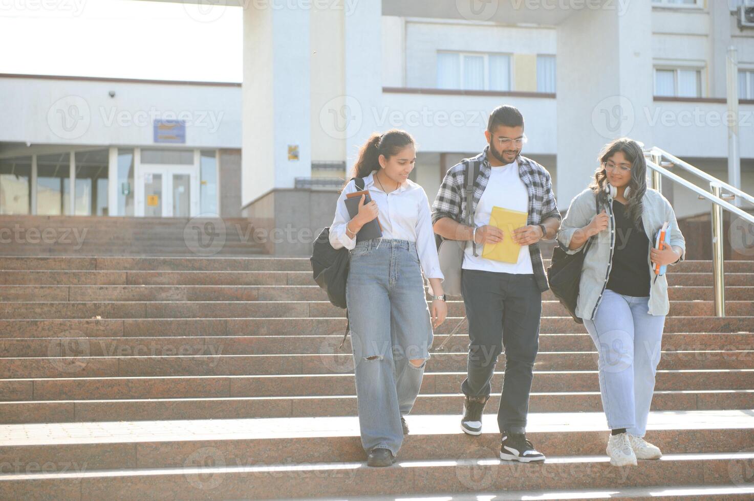 Portrait of three multi-ethnic university students embracing together standing in the campus photo