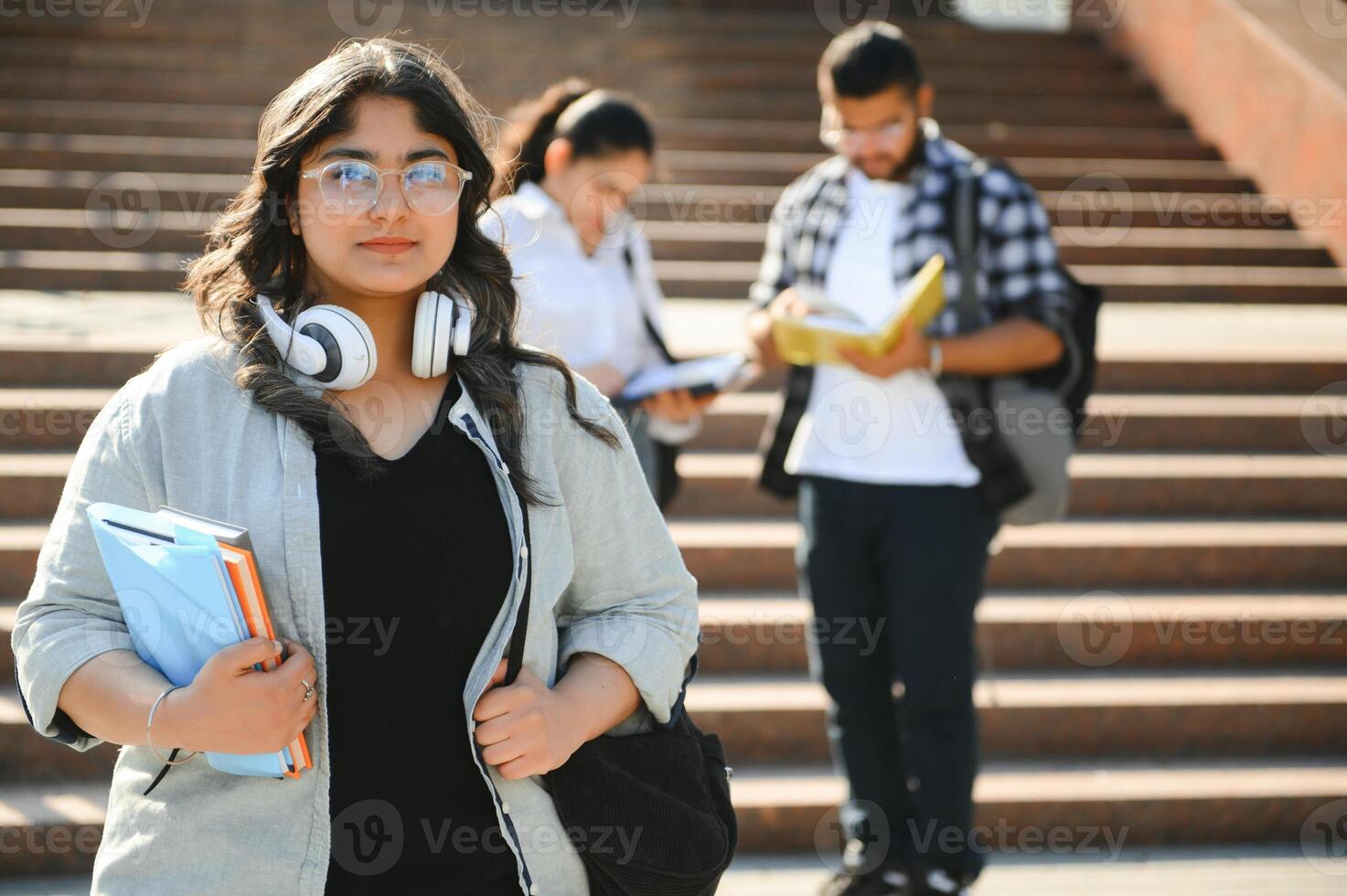 Three international students standing and holding a books photo