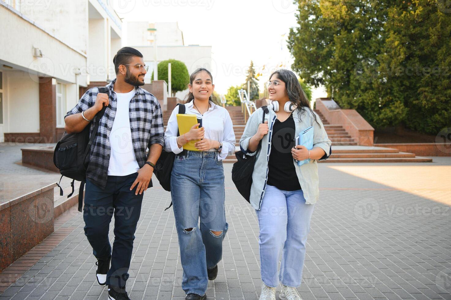 Portrait of three multi-ethnic university students embracing together standing in the campus photo