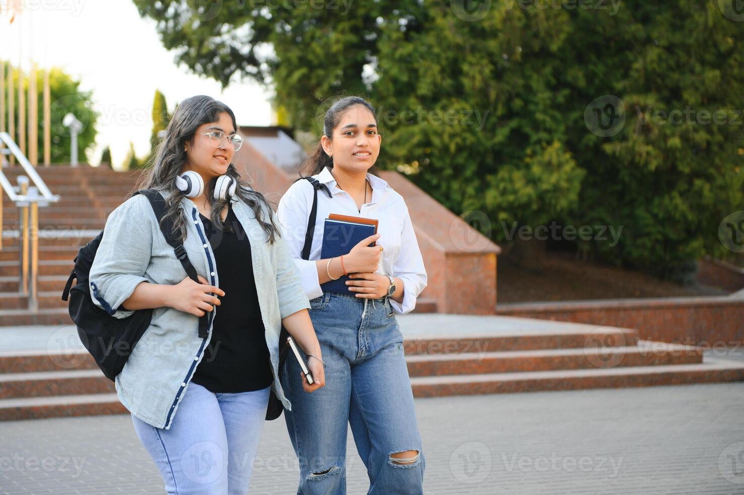 Three international students standing and holding a books photo