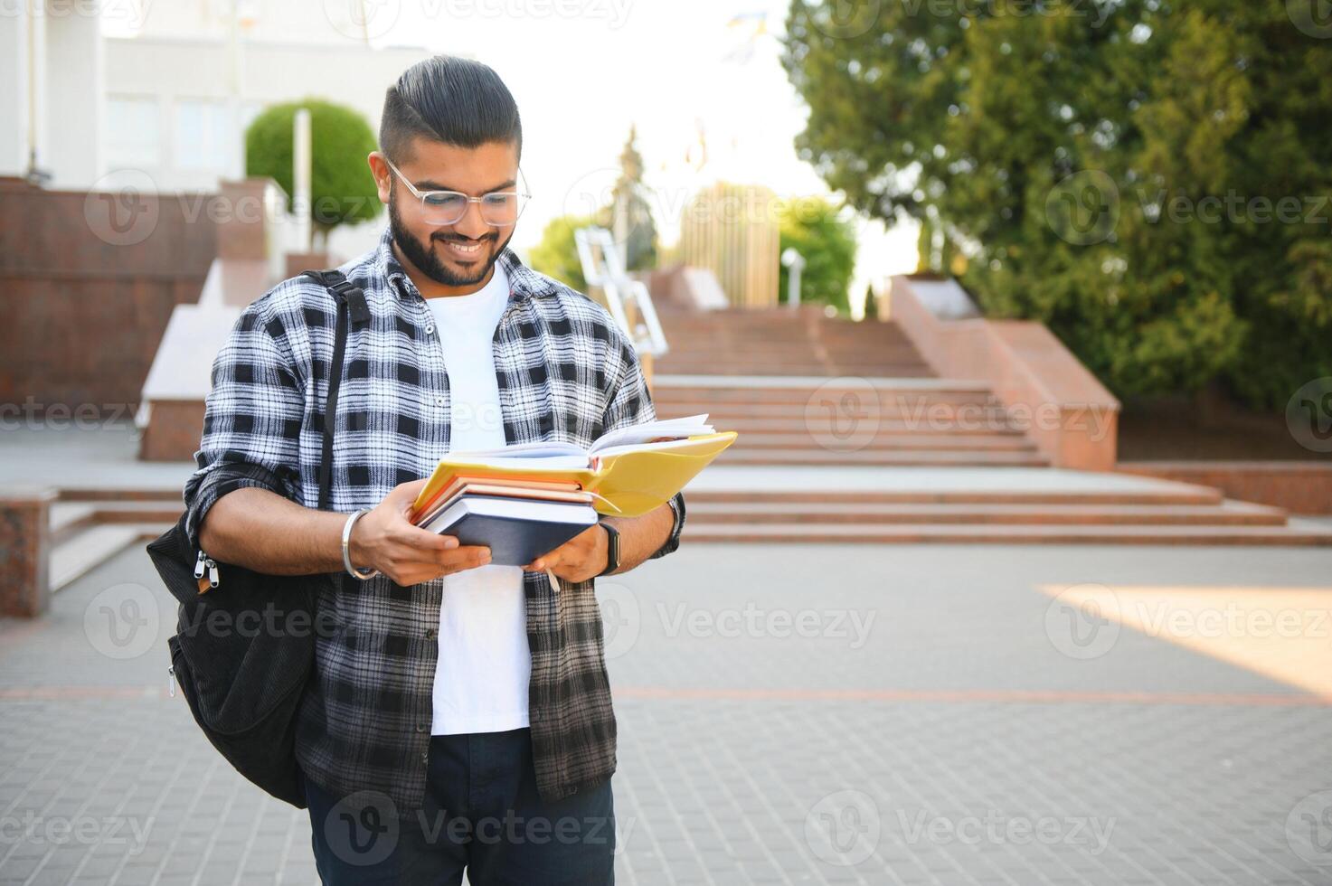 Handsome young Indian boy student with books and backpack. Education concept photo