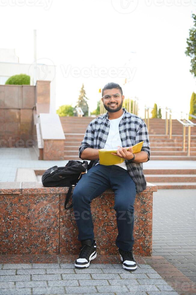 Handsome young Indian boy student with books and backpack. Education concept photo