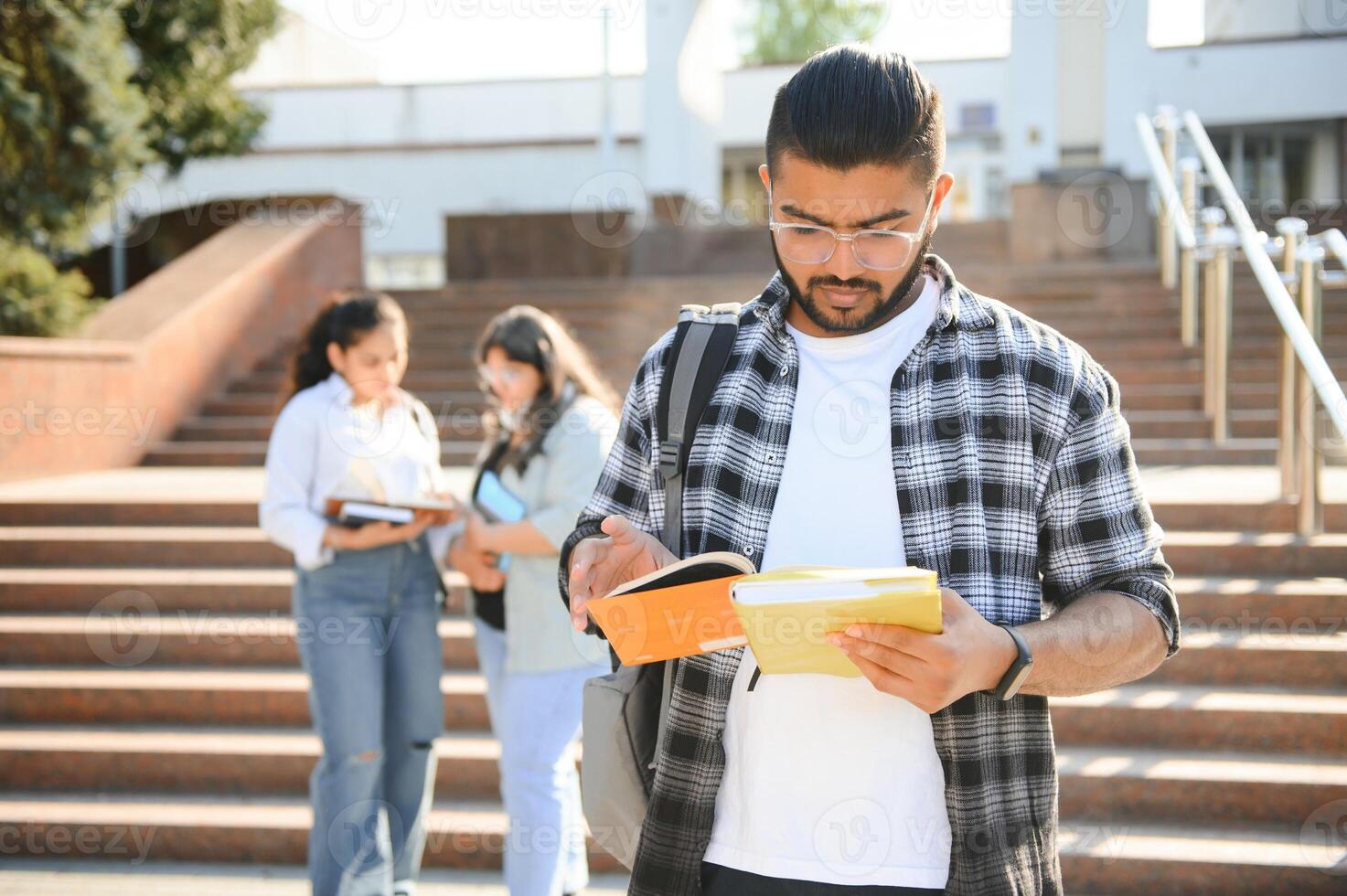 Three international students standing and holding a books photo