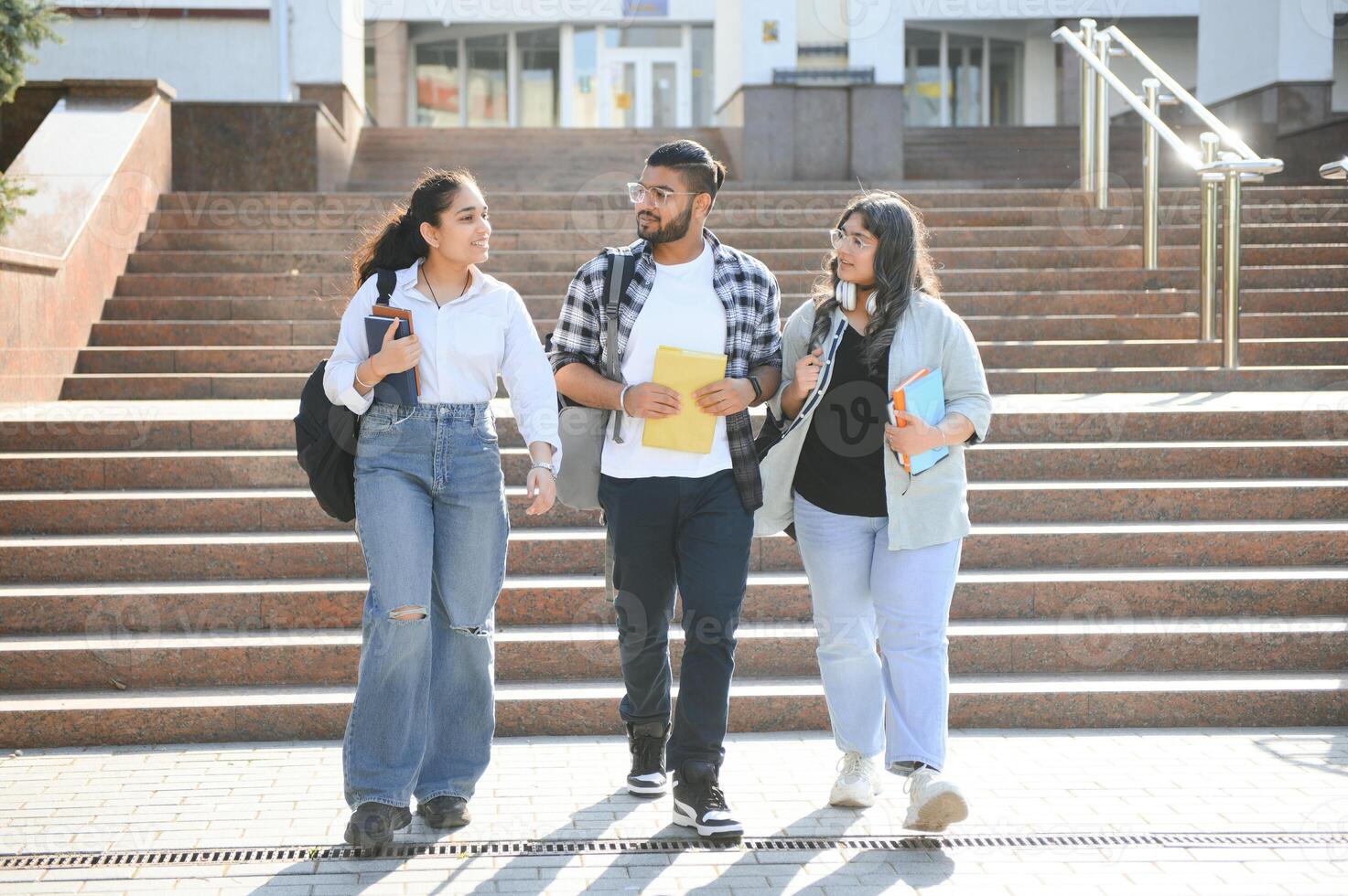 Three international students standing and holding a books photo