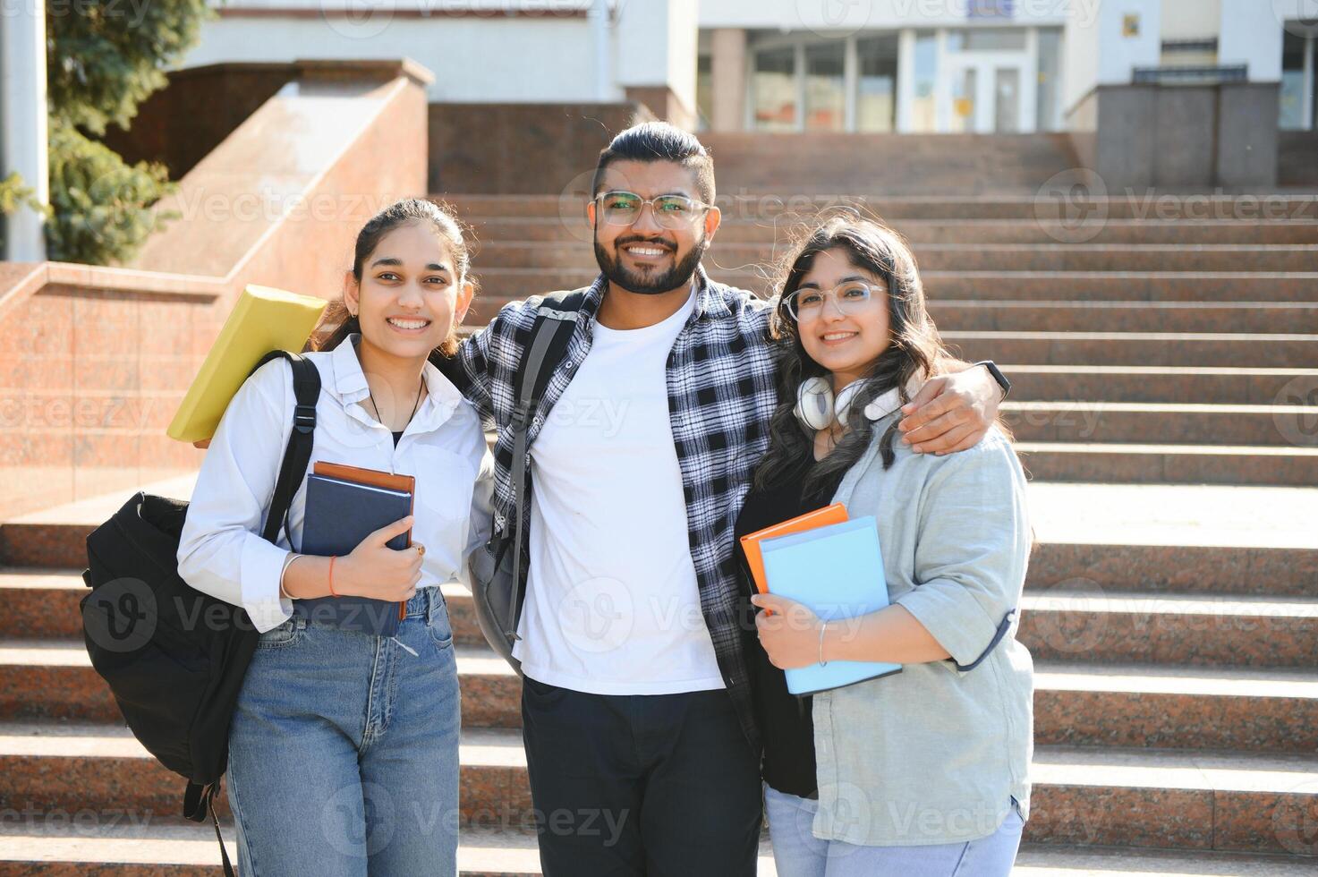 Portrait of three multi-ethnic university students embracing together standing in the campus photo