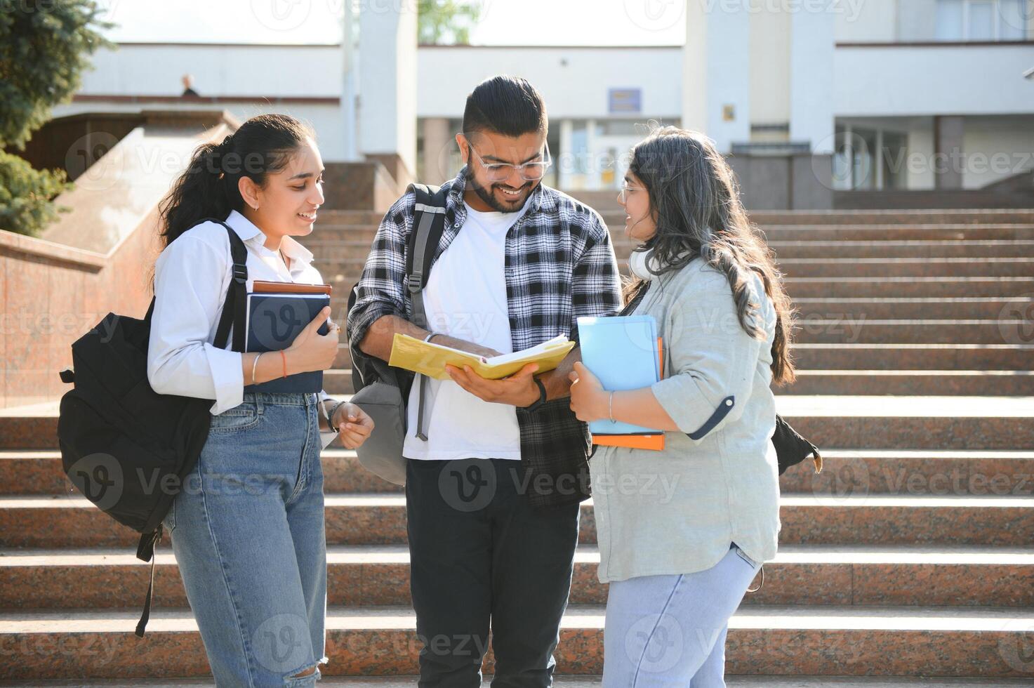 Three international students standing and holding a books photo