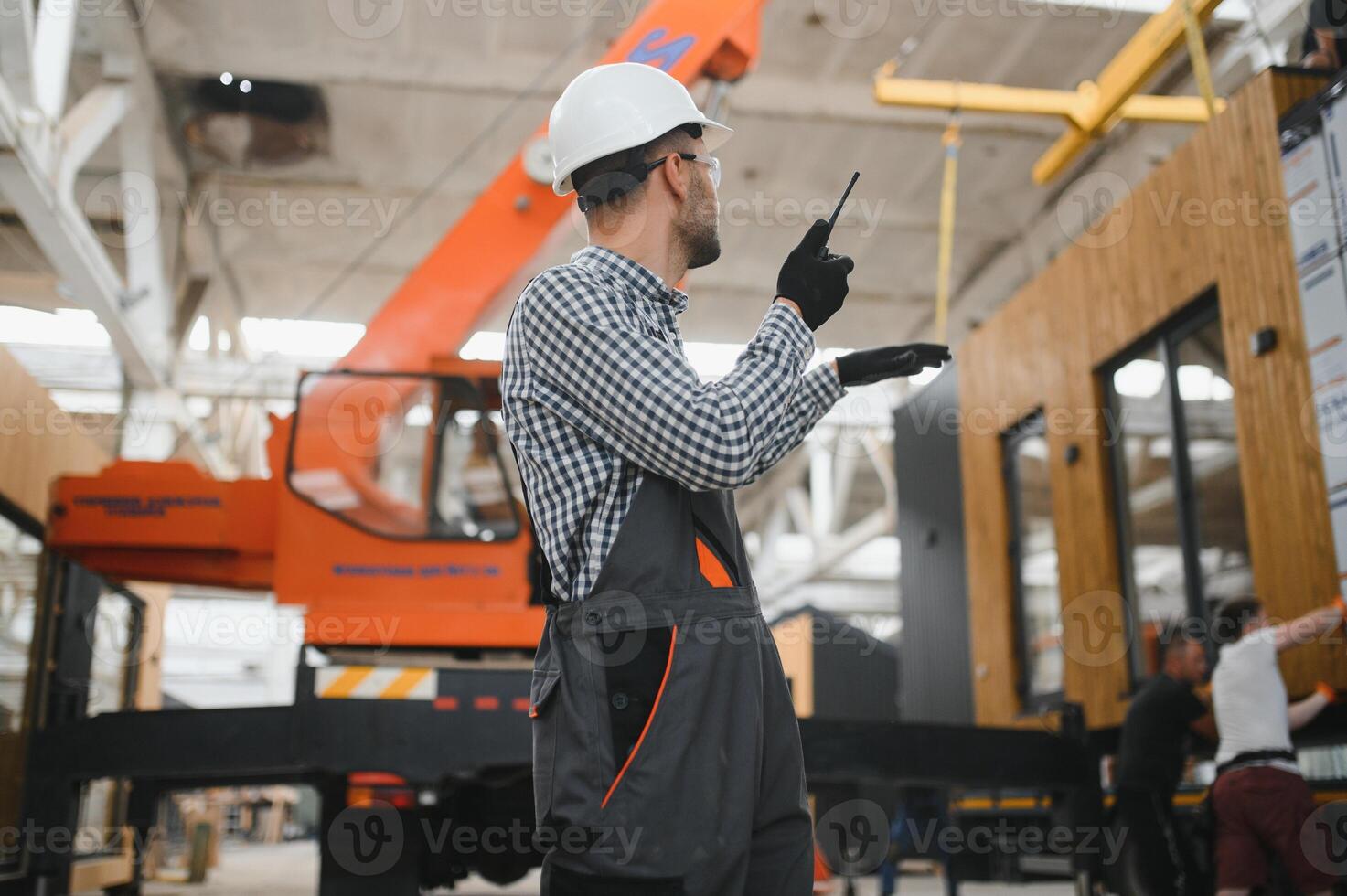 Foreman manages the loading of a prefabricated modular house to truck using walkie talkie photo
