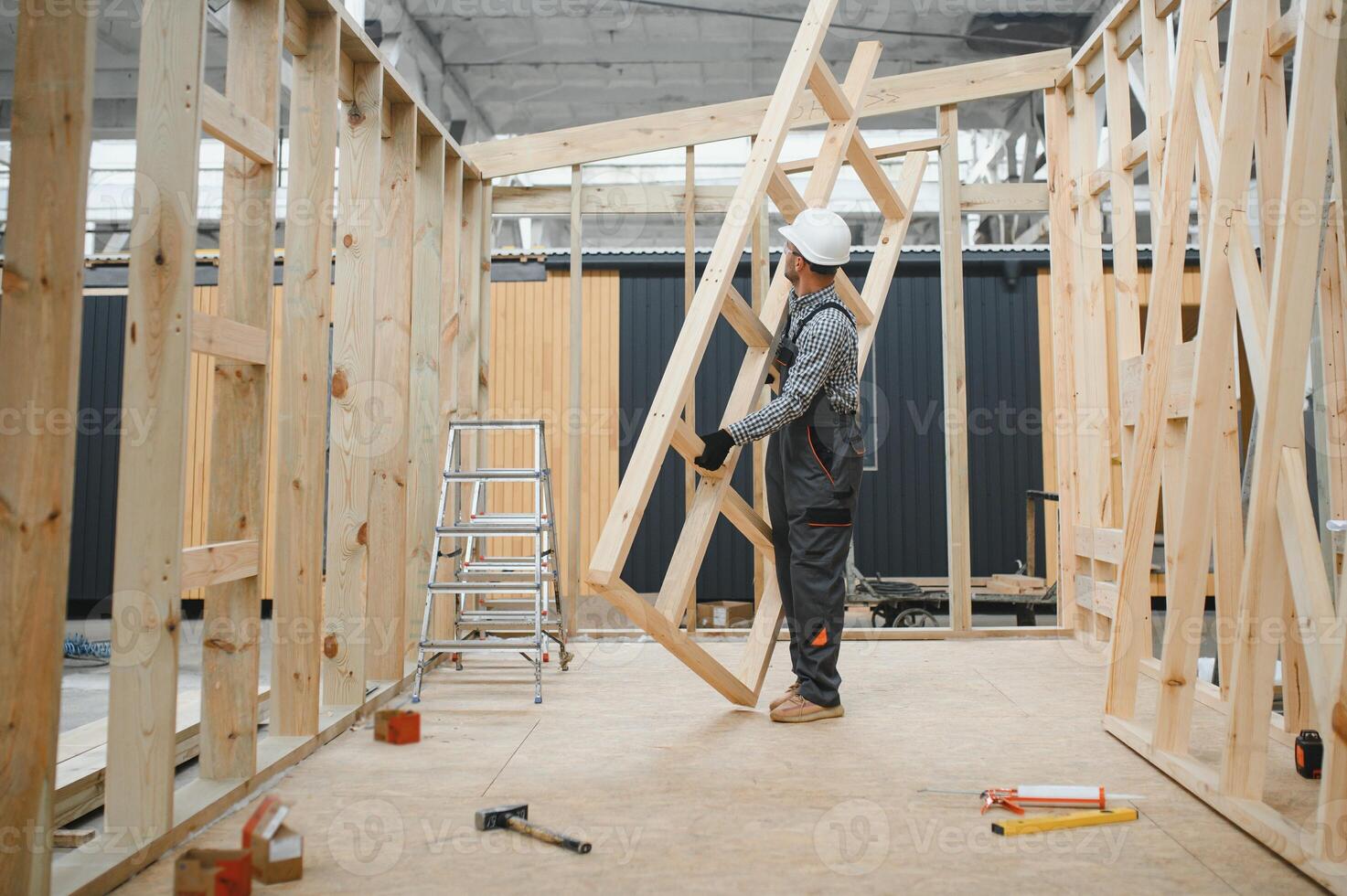 A worker or engineer in a uniform works on a construction site for the manufacture of wooden modular houses photo