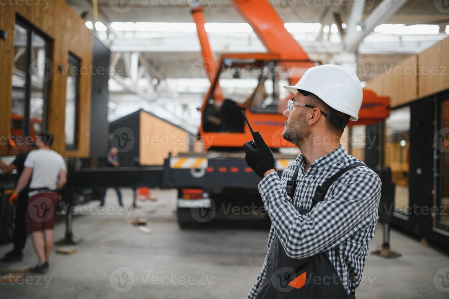 Foreman manages the loading of a prefabricated modular house to truck using walkie talkie photo