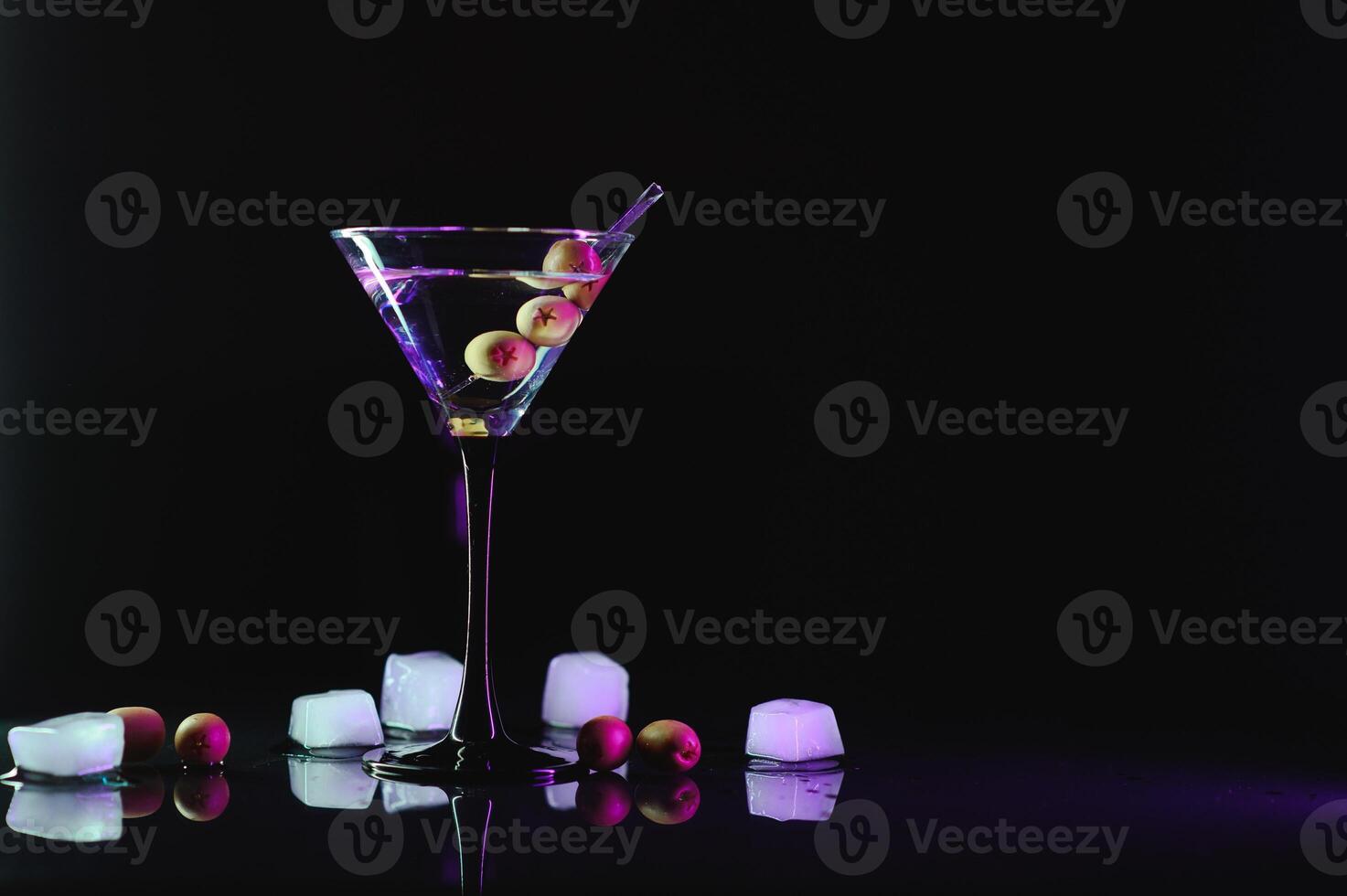 Glass of classic dry martini cocktail with olives on dark table against black background. With free space for your text photo