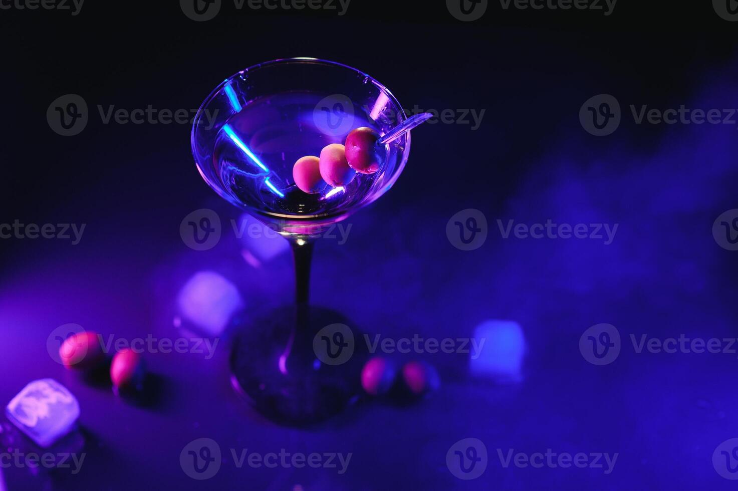 Glass of classic dry martini cocktail with olives on dark table against black background. With free space for your text photo