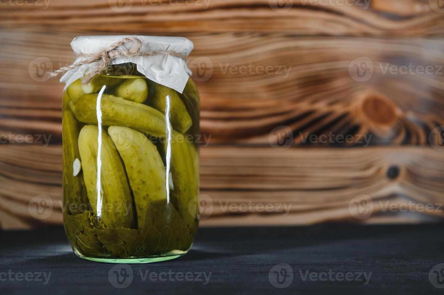 Canned cucumbers and tomatoes with craft lids on a wooden background. Cucumbers and tomatoes with place for text. Stocks of canned food. Harvest, stocks for the winter. photo