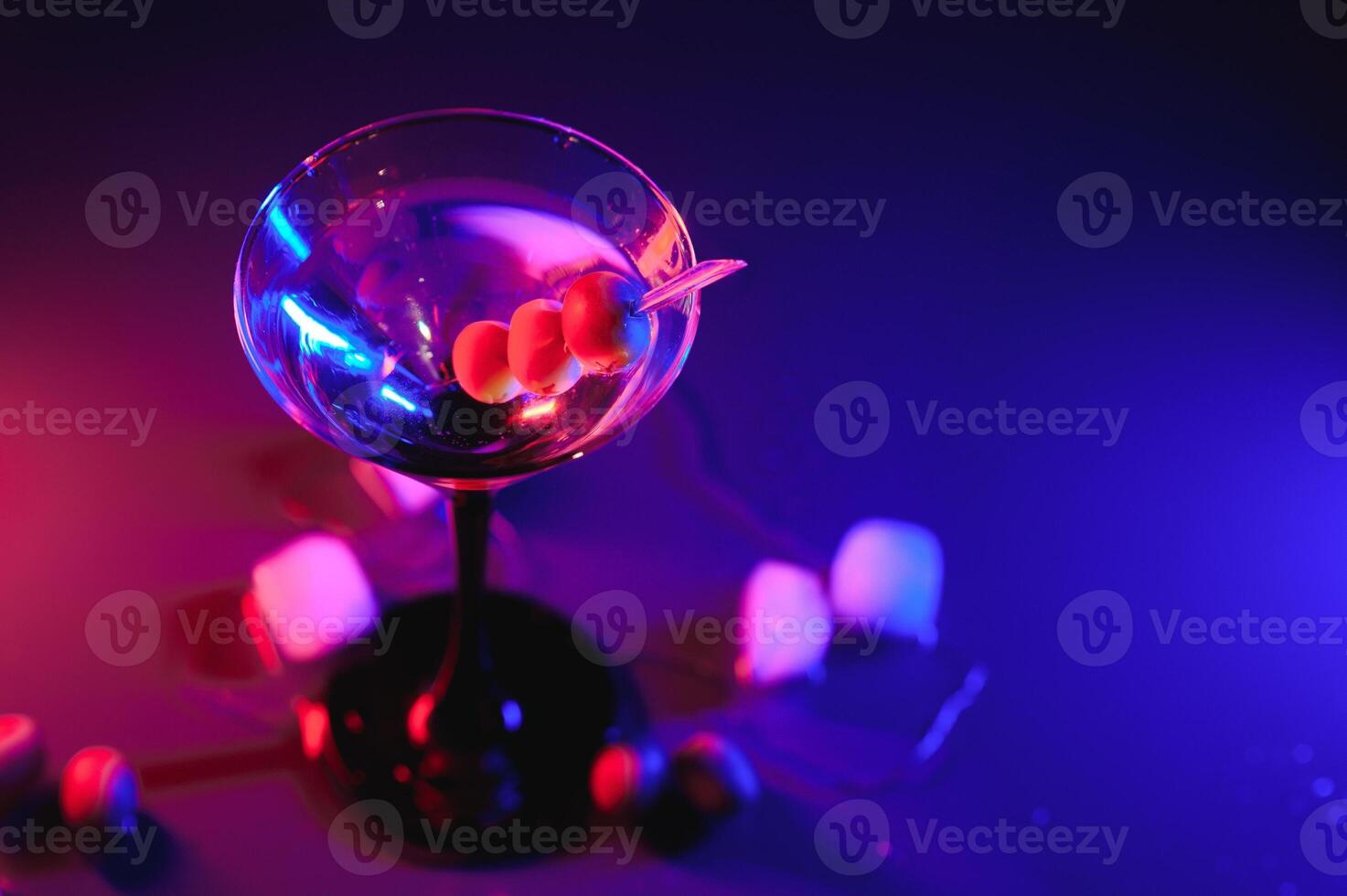 Martini glass and olives on a black background with neon lights photo