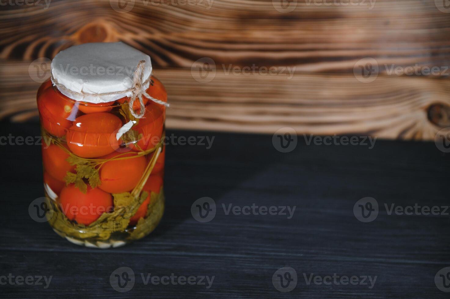 Homemade pickled tomatoes in glass jars on rustic wooden background. Fermented tomatoes in transparent glass. Homemade canned tomatoes. photo