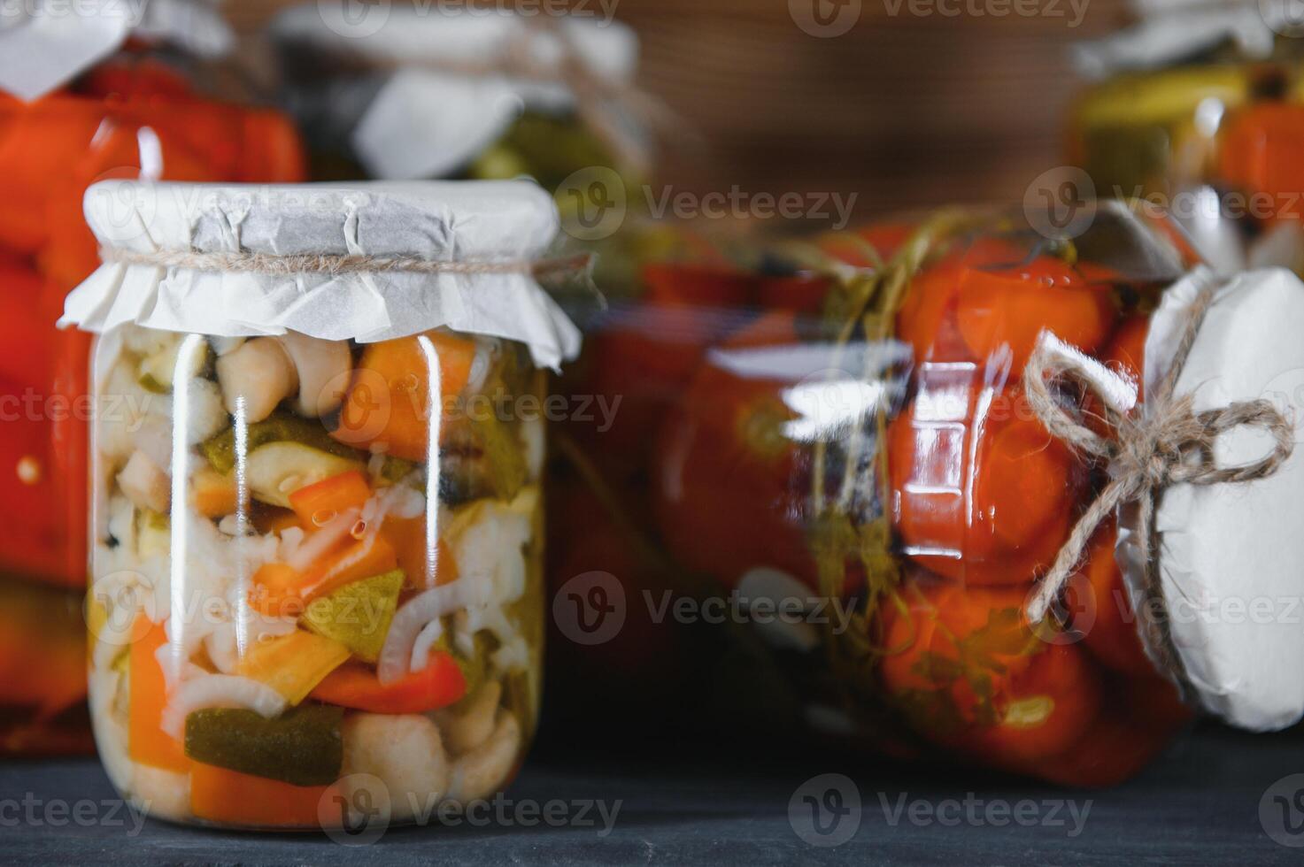 Canned cucumbers and tomatoes with craft lids on a wooden background. Cucumbers and tomatoes with place for text. Stocks of canned food. Harvest, stocks for the winter. photo