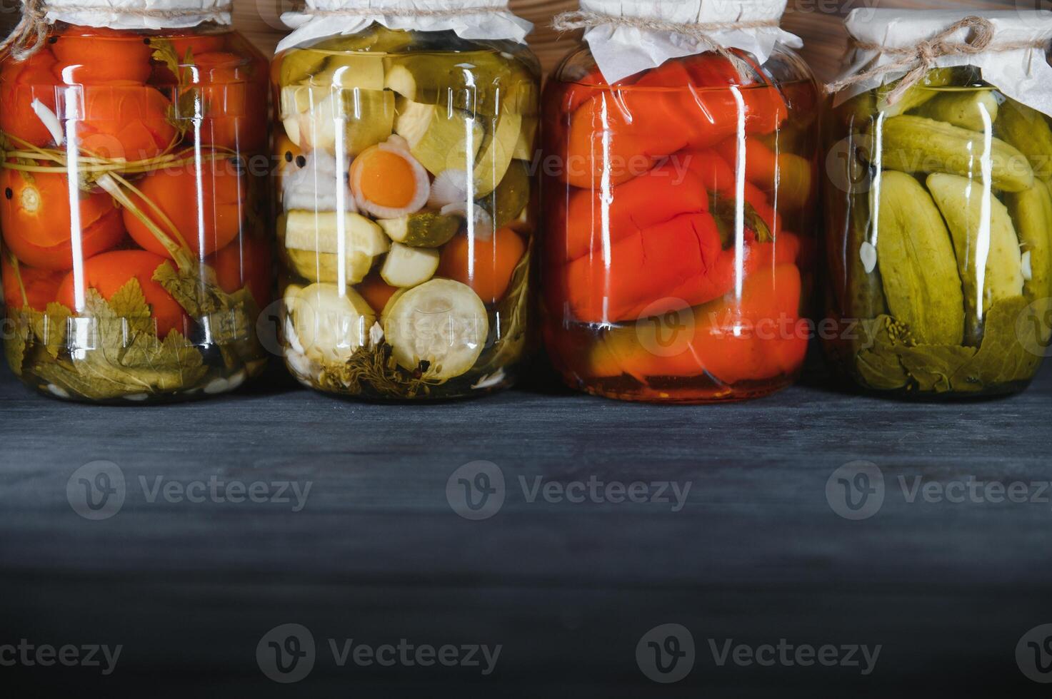 Jars of pickled vegetables on rustic wooden background photo