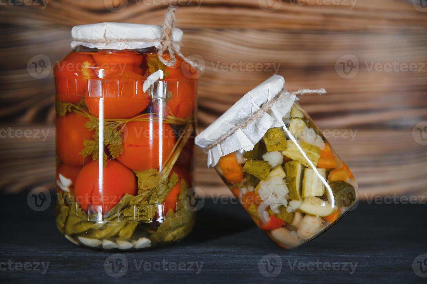Glass jars with pickled cucumbers pickles, pickled tomatoes and cabbage. Jars of various pickled vegetables. Canned food in a rustic composition. photo