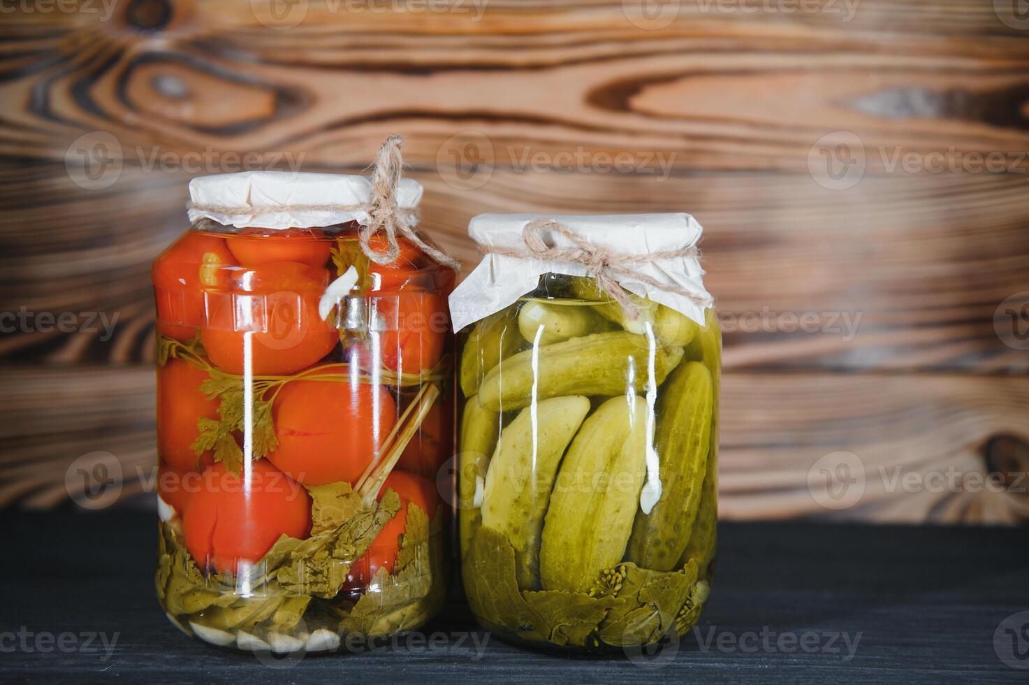 Canned cucumbers and tomatoes with craft lids on a wooden background. Cucumbers and tomatoes with place for text. Stocks of canned food. Harvest, stocks for the winter. photo
