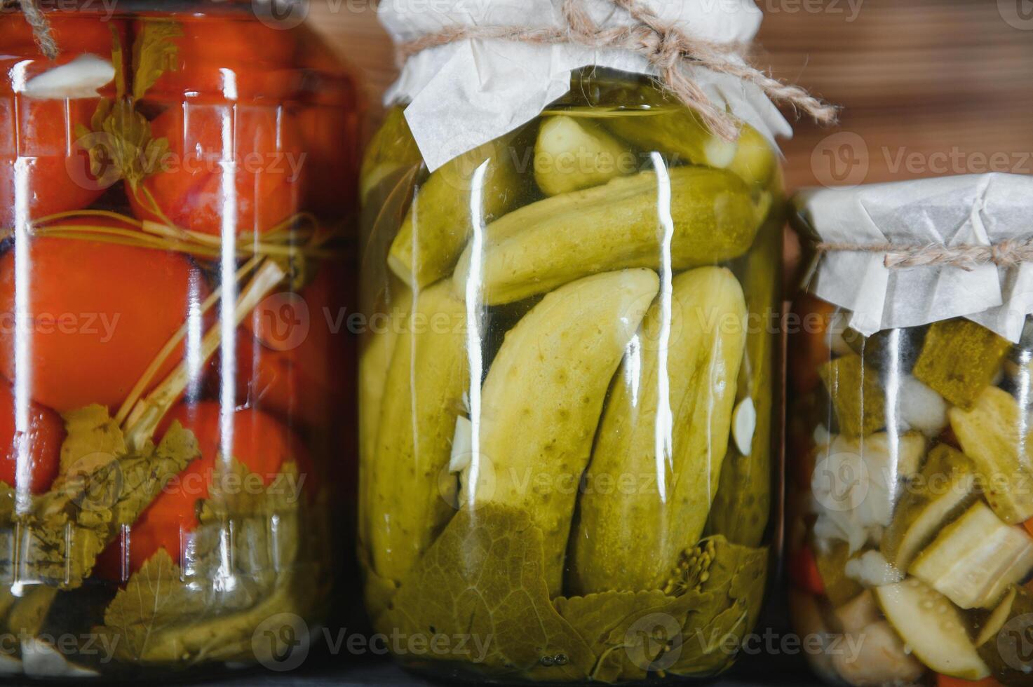 Canned cucumbers and tomatoes with craft lids on a wooden background. Cucumbers and tomatoes with place for text. Stocks of canned food. Harvest, stocks for the winter. photo