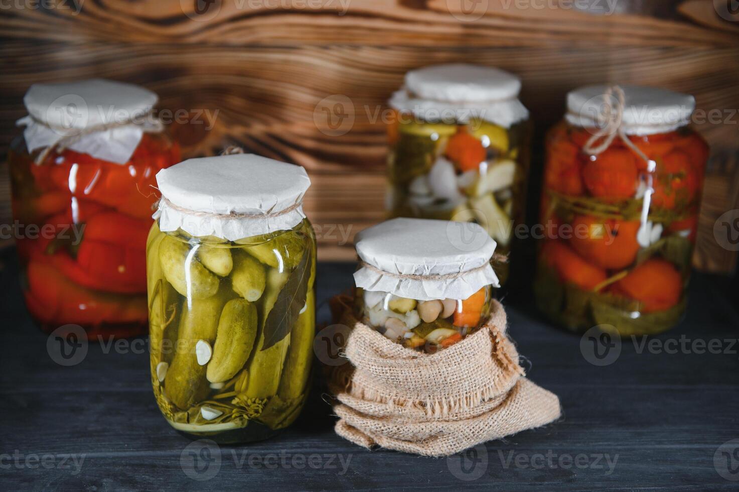 Glass jars with pickled cucumbers pickles, pickled tomatoes and cabbage. Jars of various pickled vegetables. Canned food in a rustic composition. photo