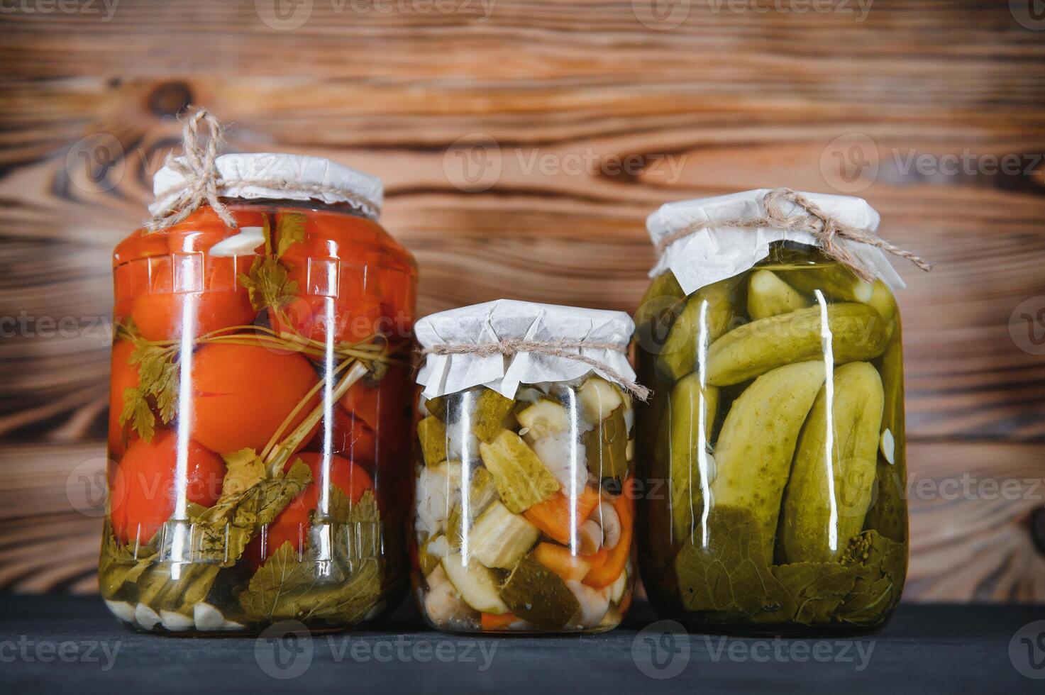 Canned cucumbers and tomatoes with craft lids on a wooden background. Cucumbers and tomatoes with place for text. Stocks of canned food. Harvest, stocks for the winter. photo