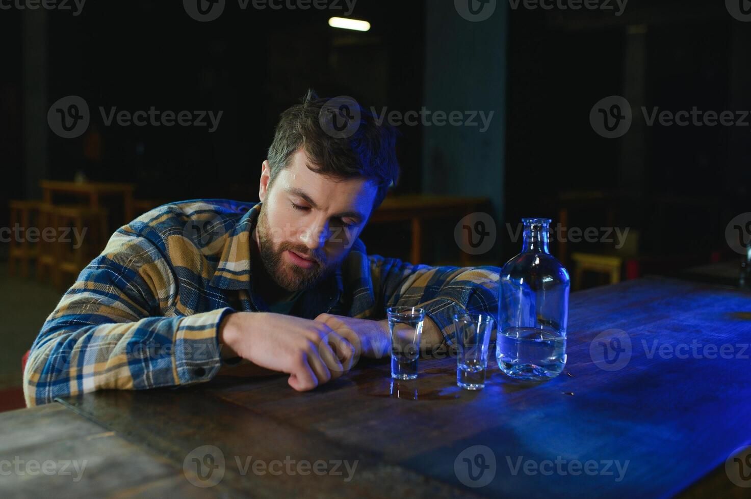 It was a hard day. Depressed young man drinking vodka in bar photo