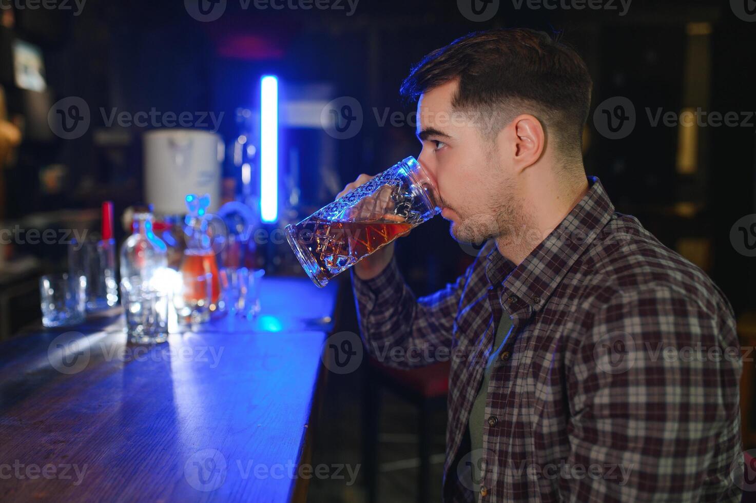 Handsome bearded man drinking beer at the bar counter in pub photo