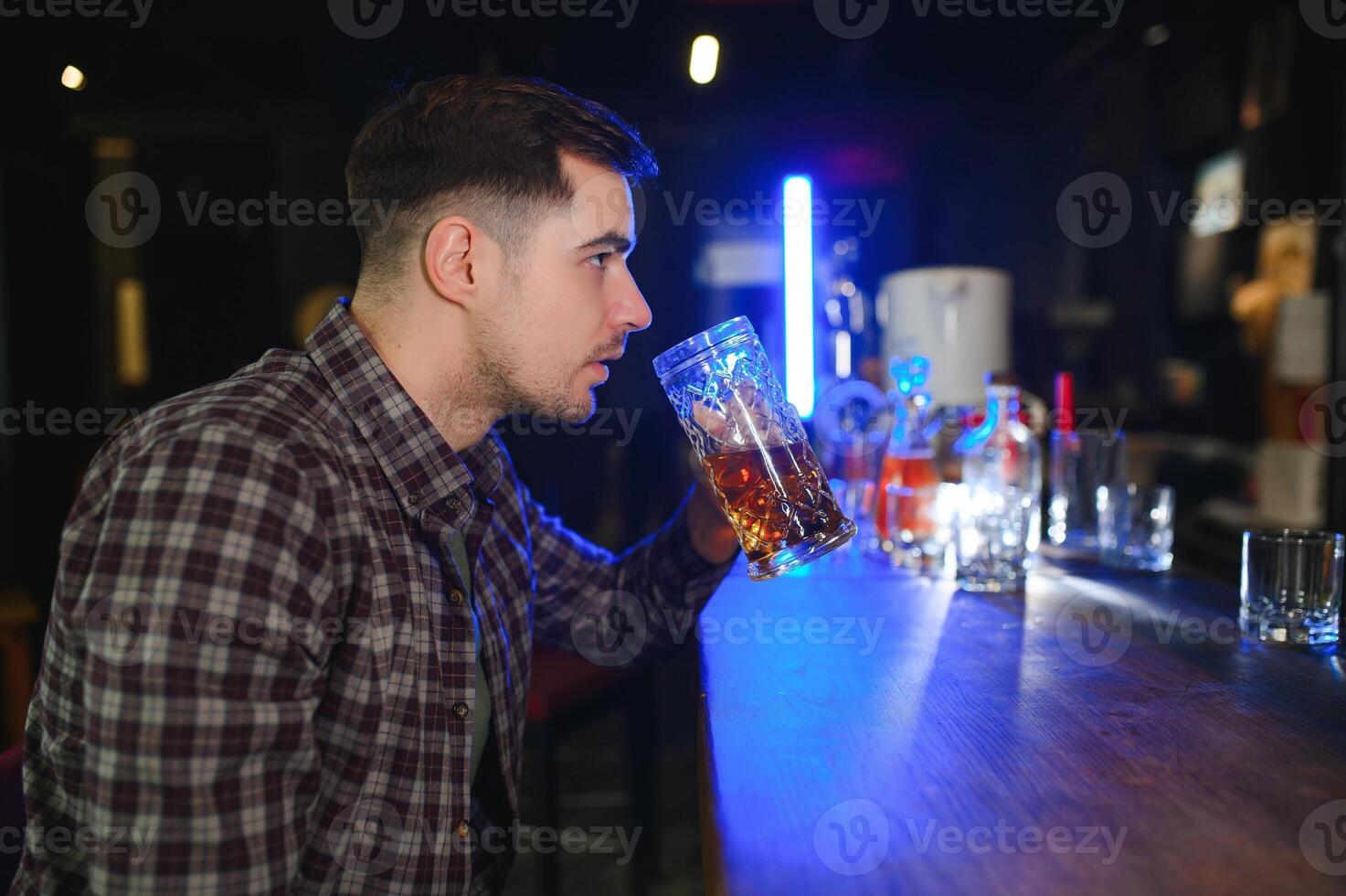Handsome bearded man drinking beer at the bar counter in pub photo