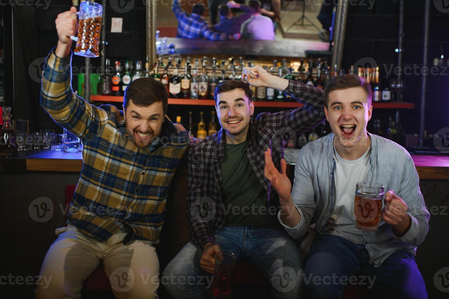 Group of excited friends in beer pub watching sports match photo