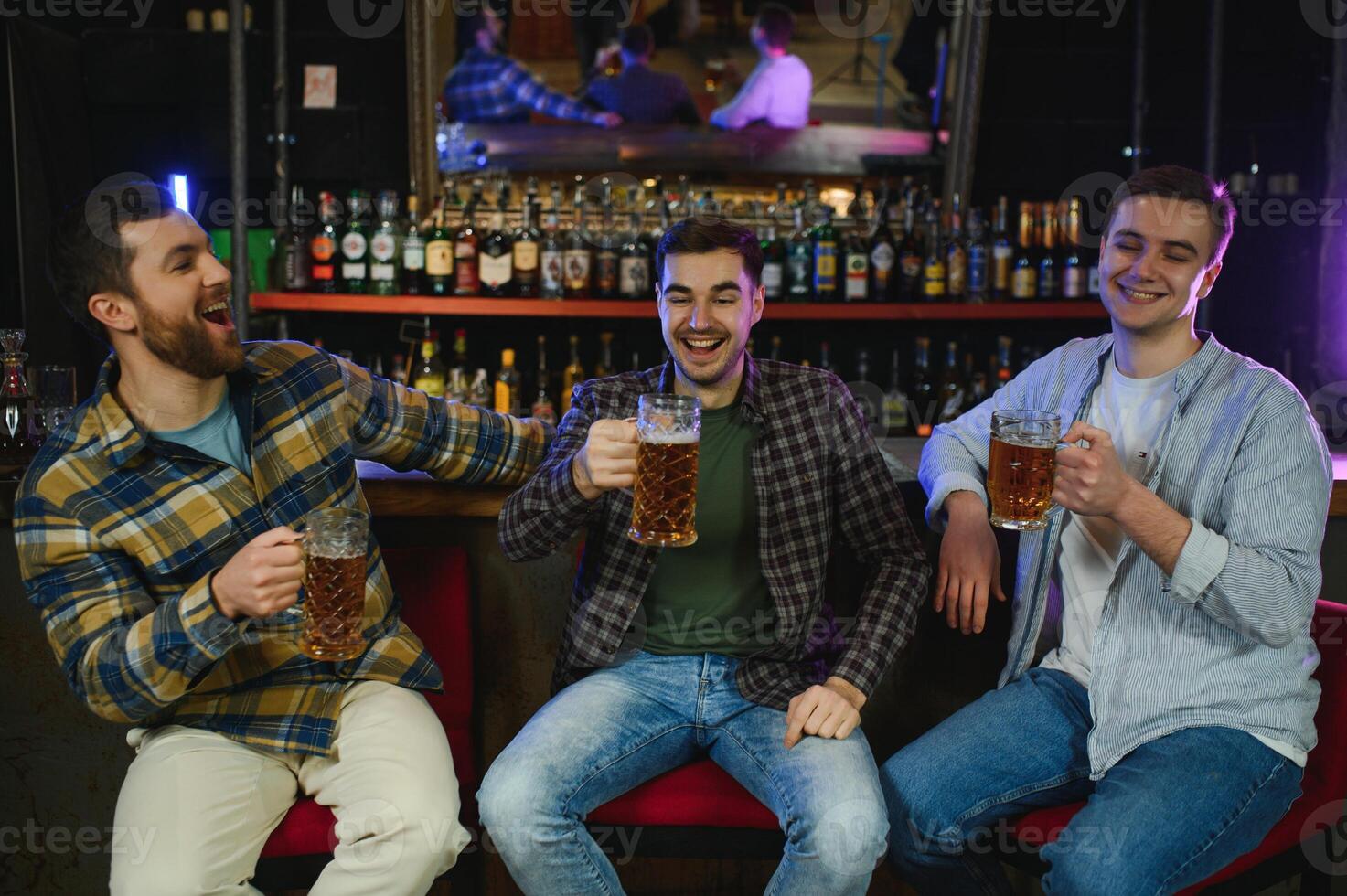 Friends resting in the pub with beer in hands. Having conversation. photo
