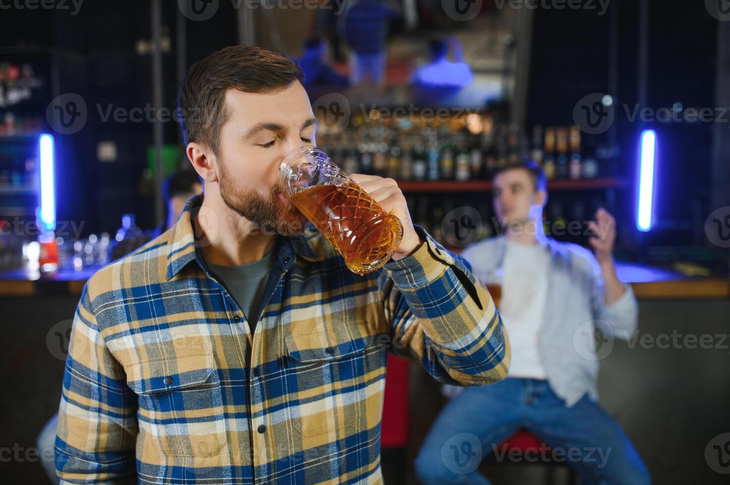 Night in bar. Portrait of cheerful men drinking beer at the bar photo