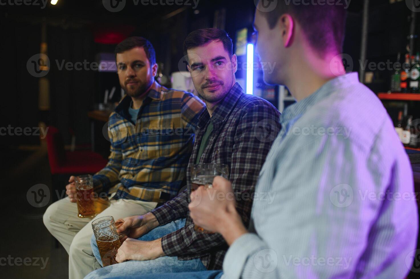 Friends having fun. Happy young men in casual wear drinking beer in pub. photo
