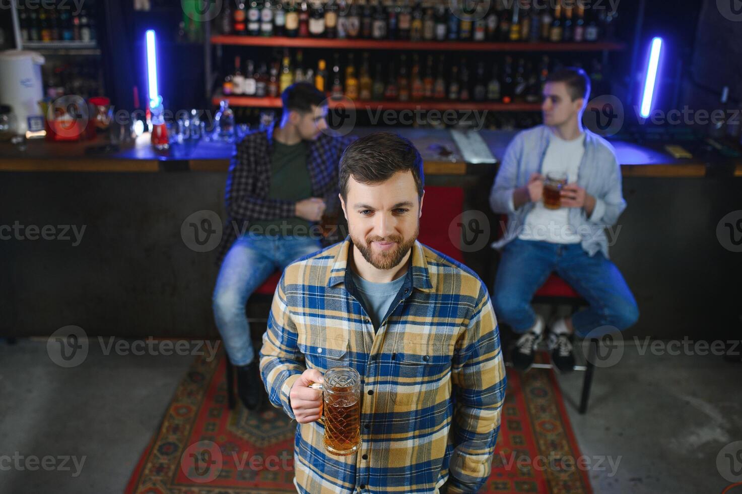 Night in bar. Portrait of cheerful men drinking beer at the bar photo