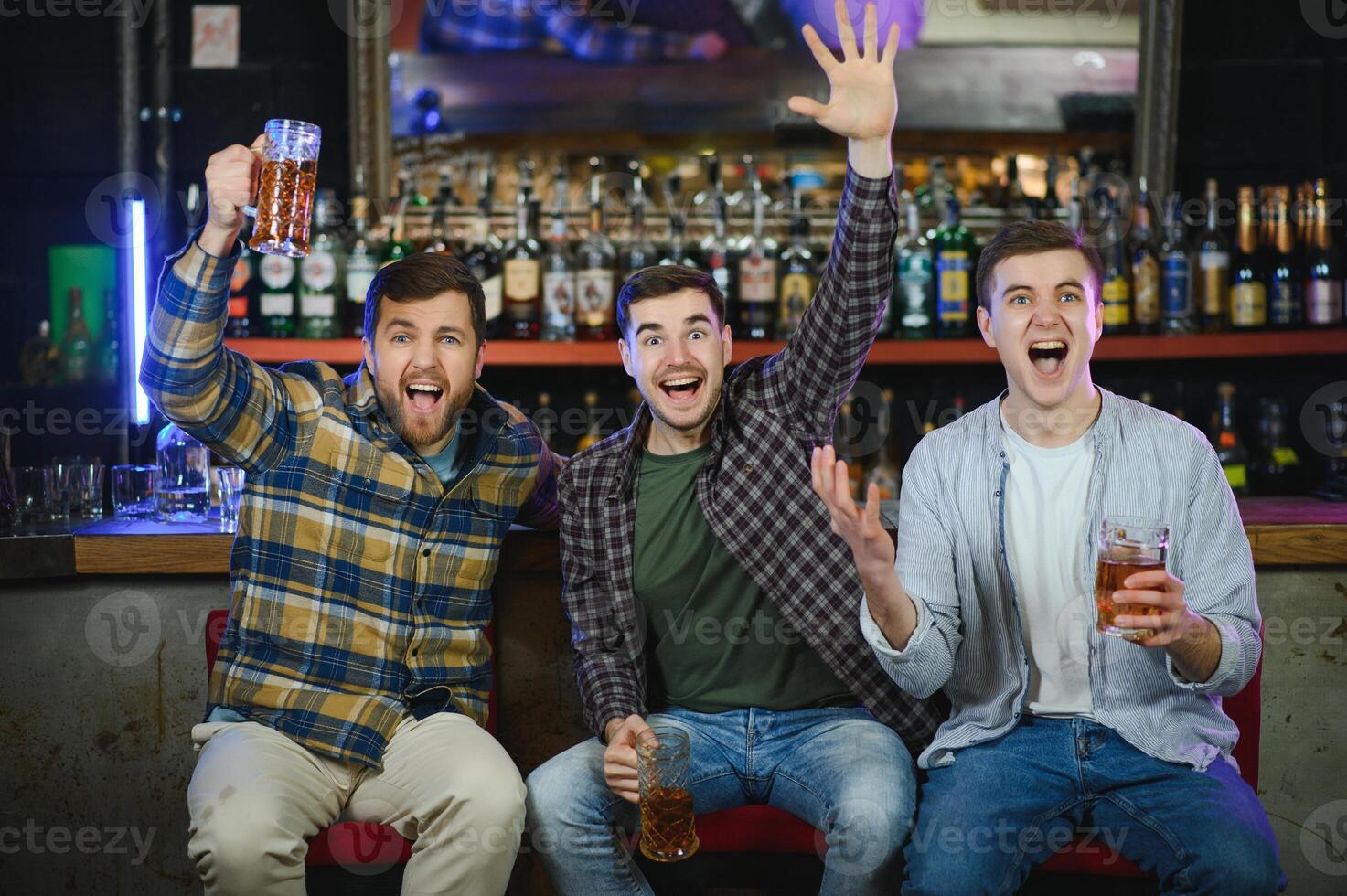 Soccer fans at the bar. Happy football fans cheering at bar and drinking beer while bartender serving beer at the background photo