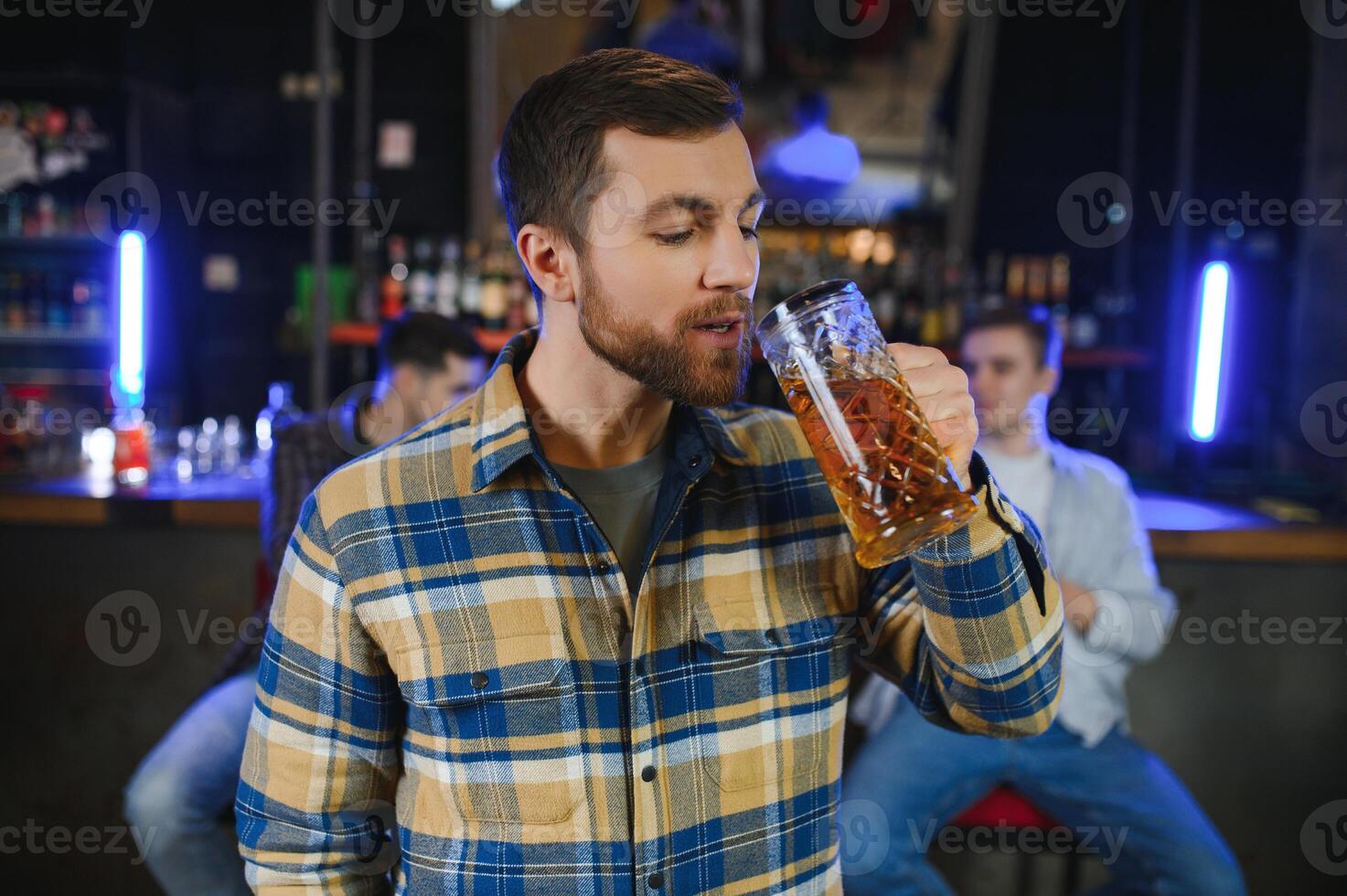 Night in bar. Portrait of cheerful men drinking beer at the bar photo