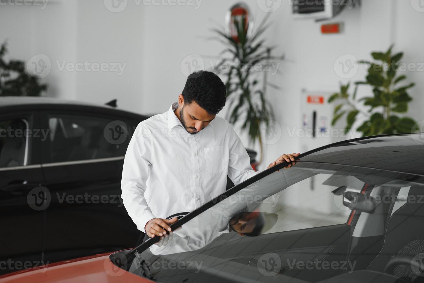 A young Indian man chooses a new car at a car dealership photo