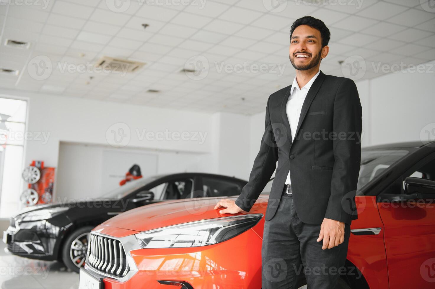 indian cheerful car salesman showing new car at showroom photo