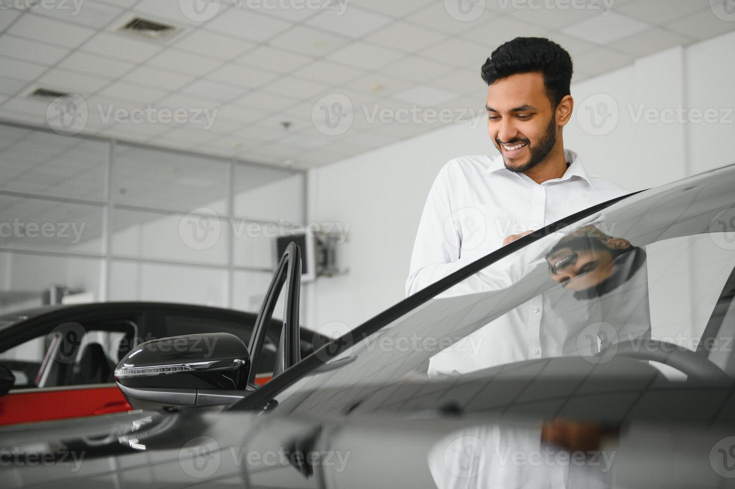 happy indian man checking car features at showroom photo