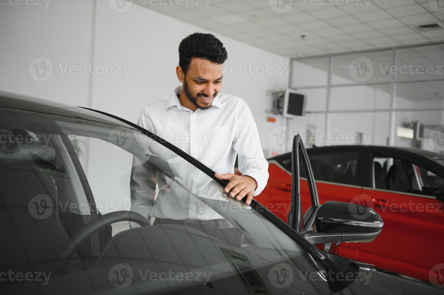happy indian man checking car features at showroom photo