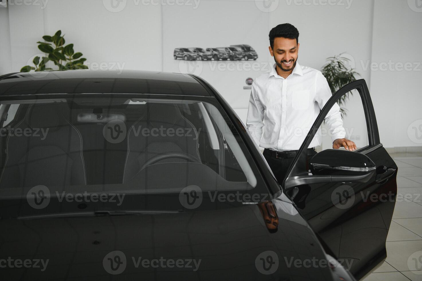 happy indian man checking car features at showroom photo