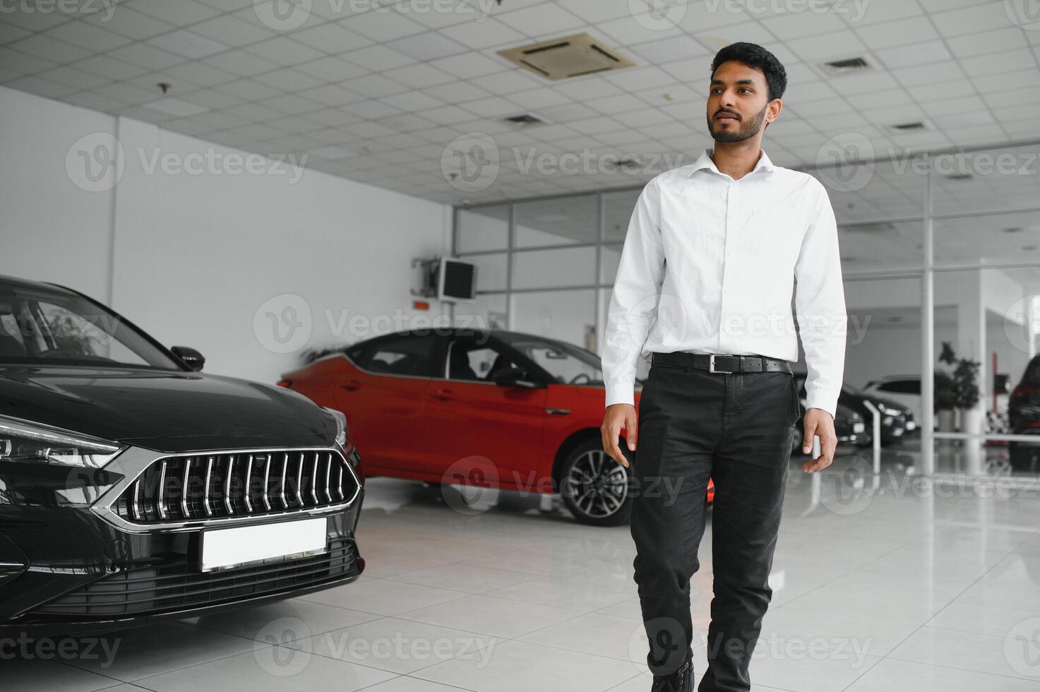 Successful indian businessman in a car dealership - sale of vehicles to customers. photo
