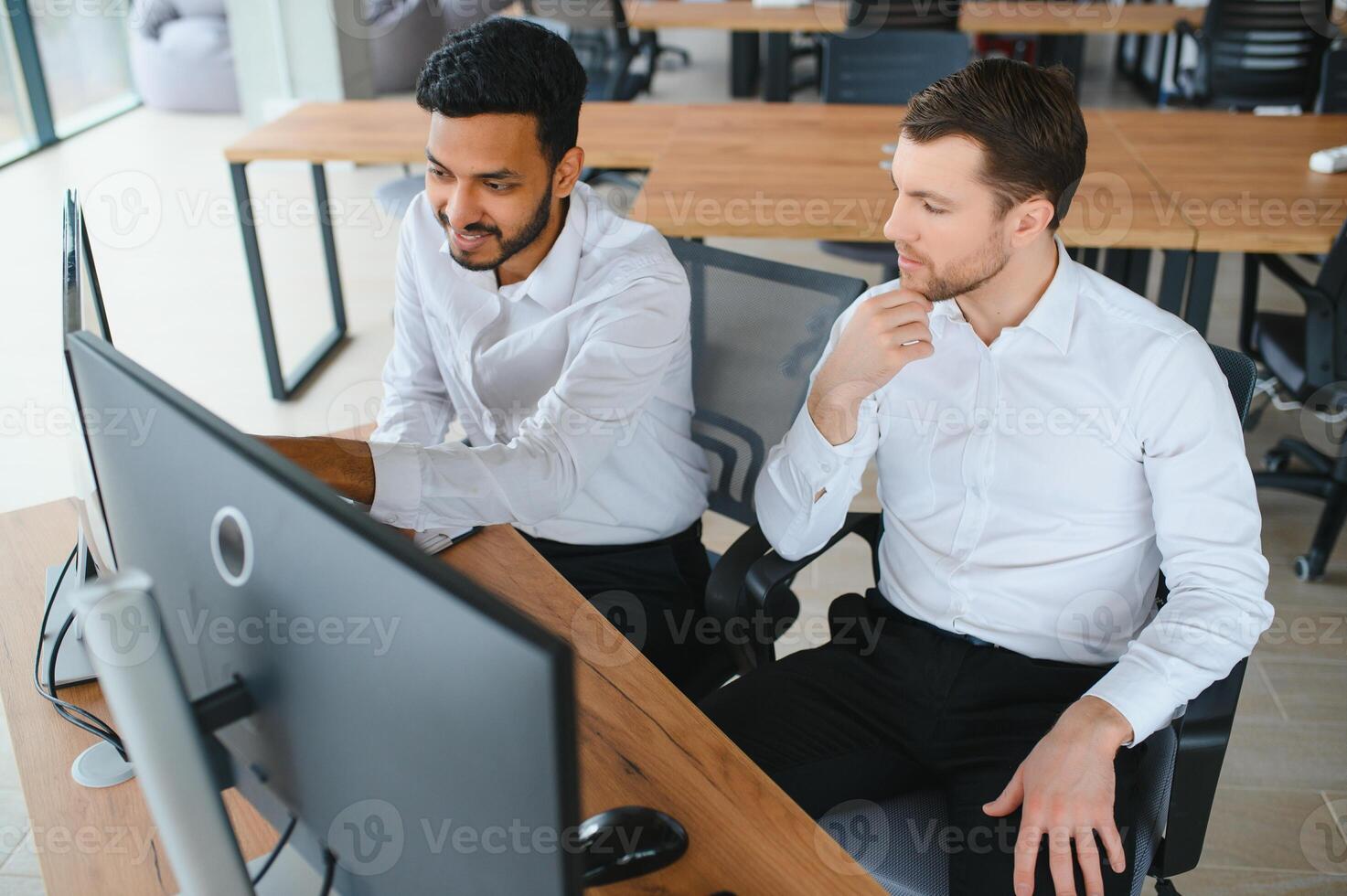 Two successful trader sitting in office and looking at screen, checking cryptocurrency information data on finance market graph, pointing on monitor photo